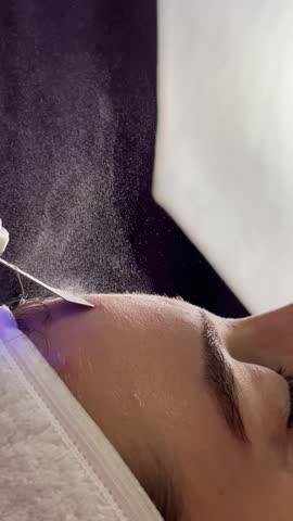 Facial cleansing with ultrasound scrubber. Woman receiving ultrasound facial peeling and cleansing. Cosmetology and face skin care. Facial treatment