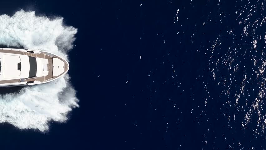 Aerial overhead close up view of a bow of a luxury yacht sailing with high speed over the ocean with copy space
