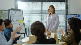 Young modern corporate Asian girl or female executive giving a presentation is appreciated or applauded by a diverse team of colleagues in a conference room meeting in a start-up office or business - Powered by Shutterstock - Get 15% off with code: PIKWIZARD15