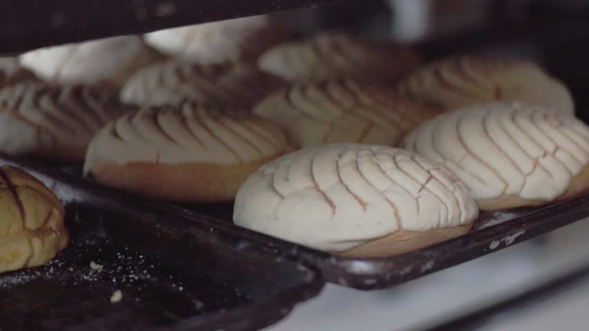 Freshly baked pastries on a baking tray inside a bakery oven, cooling after baking.