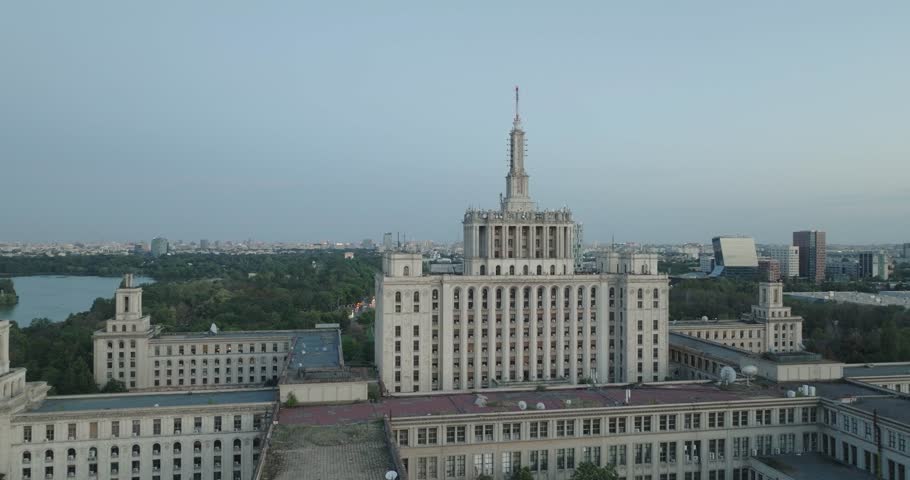 Aeriel View of the Casa Presei in Bucharest Romania at dusk with full moon rising and city skyline. Brutalist Soviet architecture and abandoned building in 4K.