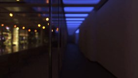 A dimly lit hallway with blue ceiling lights and silhouettes of people in the distance. - Powered by Shutterstock - Get 15% off with code: PIKWIZARD15