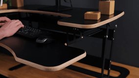Adjustable desk, height-adjustable, sit-stand desk. Hand changes height of desk with black mouse and wooden accessories visible. - Powered by Shutterstock - Get 15% off with code: PIKWIZARD15