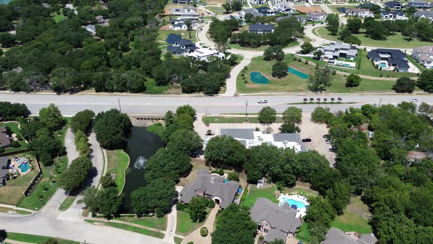 Water fountain small pond in lakeside residential neighborhood along West Southlake Boulevard, Keller, Texas, luxury mansion houses swimming pools in suburbs Dallas Fort Worth metroplex, flyover. USA