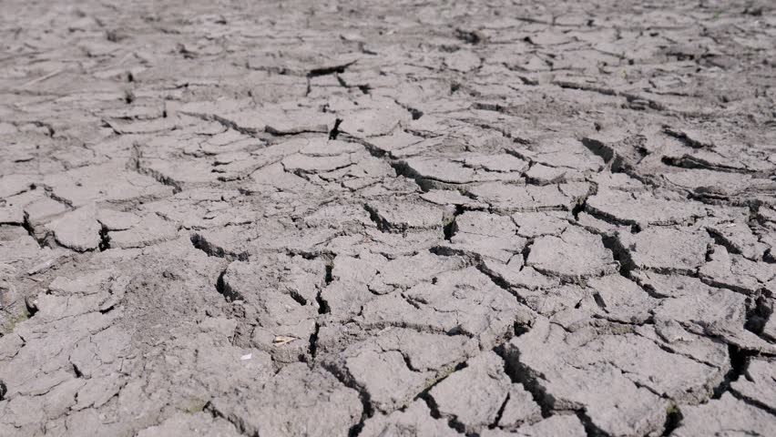 Cracked and dry soil spreads out in all directions, with deep fissures indicating a long period without water. The lifeless ground has no vegetation or water sources