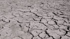 Cracked and dry soil spreads out in all directions, with deep fissures indicating a long period without water. The lifeless ground has no vegetation or water sources - Powered by Shutterstock - Get 15% off with code: PIKWIZARD15