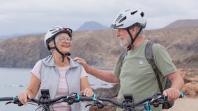 Two happy old mature people enjoying and riding bikes together to be fit and healthy outdoors. Active seniors having fun training in nature. Portrait of one old man smiling in a bike trip  - Powered by Shutterstock - Get 15% off with code: PIKWIZARD15