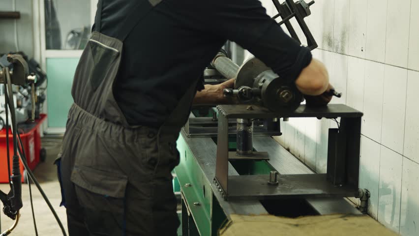 A mechanic in a car repair shop adjusts and centers the driveshaft of a truck on a specialized machine and performs computer diagnostics