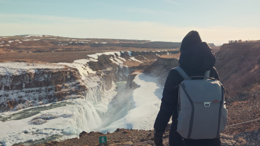 Freedom tourist woman enjoying on viewpoint of Gullfoss waterfall or Golden Falls with extreme hvita river flowing in canyon on winter at Iceland