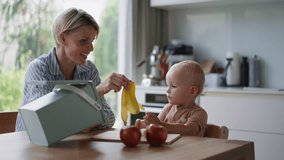 Mother teaching small baby to throw banana peel into organic waste bin. Kitchen compost bin. Sustainable living and future. - Powered by Shutterstock - Get 15% off with code: PIKWIZARD15