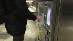 A person is standing at an ATM in the midst of a bustling urban transport station, demonstrating the significant advancements made in modern transaction technology and the convenience it offers - Powered by Shutterstock - Get 15% off with code: PIKWIZARD15