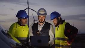 Diverse work team engineers using laptop at night wind power plant in countryside. Professional technicians discuss windmill maintenance in safety clothing. Renewable energy clean sustainable future. - Powered by Shutterstock - Get 15% off with code: PIKWIZARD15