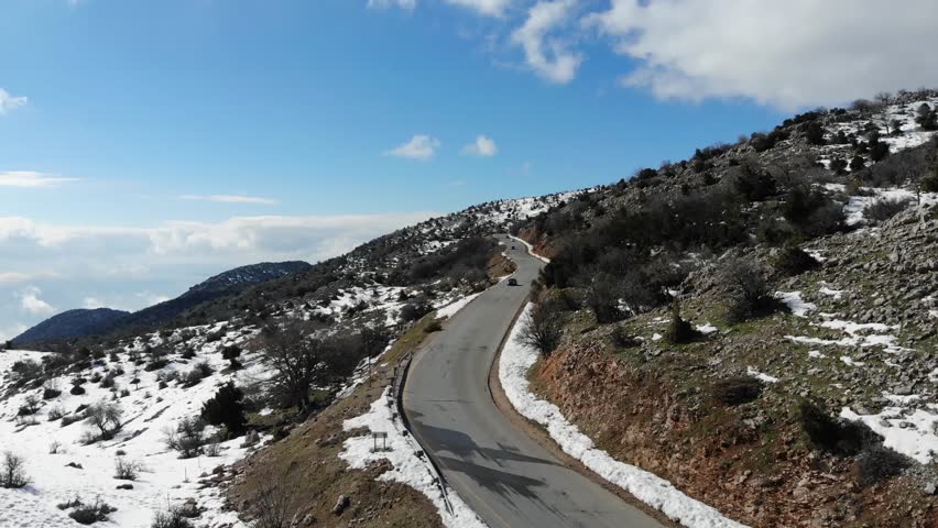 Israel Syria Border - Aerial footage of a car driving through the scenic road down snowy Mount Hermon in the Golan Heights between Israel and Syria