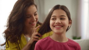 Laughing cheerful Caucasian woman female mother braiding hair hairstyle of little girl child daughter kid talking friendly conversation morning routine indoors home. Happy family motherhood adoption - Powered by Shutterstock - Get 15% off with code: PIKWIZARD15
