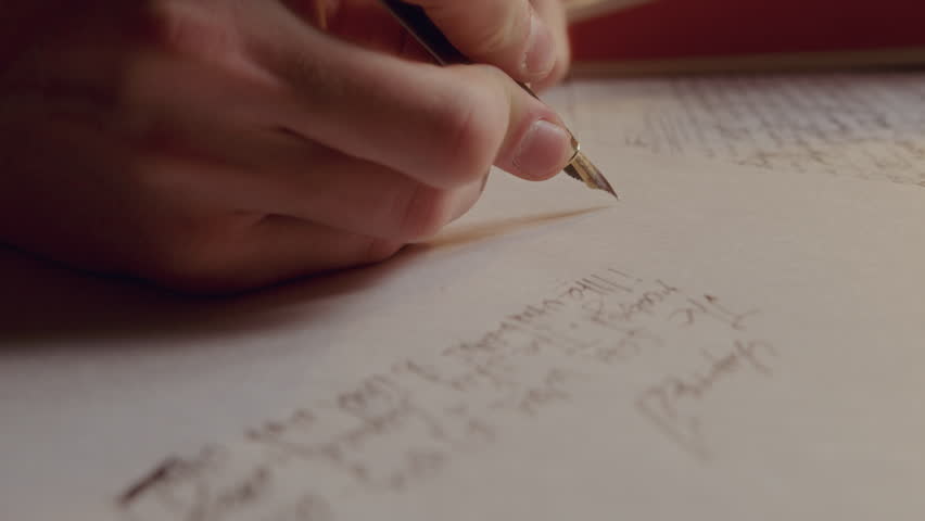 Hand of unrecognizable man writing text in English on paper page with vintage fountain pen. Extreme close-up view