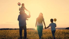 Dad mom kids on parents shoulders walking in meadow, kids playing holding pinwheel toy in hand. Happy family, child mother father weekend. Mom dad son daughter together, travel in nature. Happy child - Powered by Shutterstock - Get 15% off with code: PIKWIZARD15