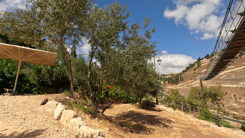 the suspension bridge over Gei Ben Hinnom near the Old City of Jerusalem, with the Mount of Olives and cloudy skies in the background.show the Israeli landscapes and historical site