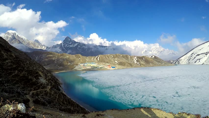 Panoramic view on Gokyo mountain valley with ice partly covered Gokyo lake and Gokyo village in Nepal in Himalayas on height 4750 meters in a sunny day. Time lapse video. Landscapes theme