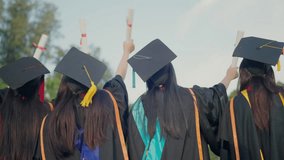 A group of women wearing graduation caps and gowns are standing together. They are all holding their graduation certificates - Powered by Shutterstock - Get 15% off with code: PIKWIZARD15