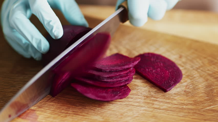 Clean cooking. Woman cutting fresh beetroot in protective gloves, close up