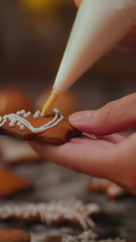 Vertical monitor. House. A caring mother in a kitchen apron carefully applies a festive design to gingerbread cookies. Housewife decorating Christmas cookies, Thanksgiving tradition