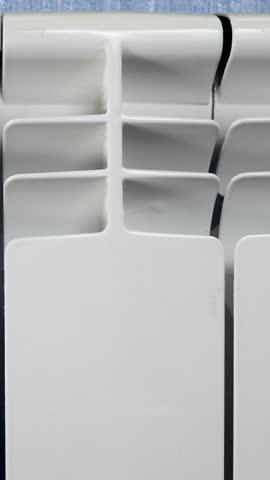 Central heating system with white metal radiator. Keeps room warm during cold winter. Effective for maintaining comfortable temperature indoors. Essential for heating and plumbing in household