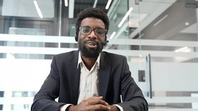 Webcam view. African american businessman engaged in video call, wearing headset, in modern office looking at camera. Focus on digital communication, professional presentation, business interaction - Powered by Shutterstock - Get 15% off with code: PIKWIZARD15