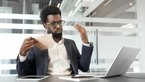 African american businessman in formal suit experiencing discomfort at work uses fan to cool down at desk. Frustrated black man suffering from heat sitting at desk with laptop in modern office setting - Powered by Shutterstock - Get 15% off with code: PIKWIZARD15
