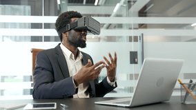 African American businessman uses virtual reality headset in office setting. Confident man in a suit using VR glasses for video call and online chat at workplace. Engages with innovative technology - Powered by Shutterstock - Get 15% off with code: PIKWIZARD15