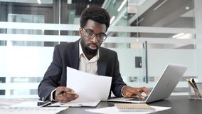Busy thoughtful african american businessman analyzing financial documents checking data on laptop while sitting at desk at a workplace in a business office. Financier deals with financial report - Powered by Shutterstock - Get 15% off with code: PIKWIZARD15