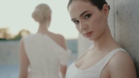 Two elegant women in white dresses, one facing the camera and the other turned away, exuding confidence and serenity in an outdoor setting. Elegant Women Posing in White Dresses - Powered by Shutterstock - Get 15% off with code: PIKWIZARD15