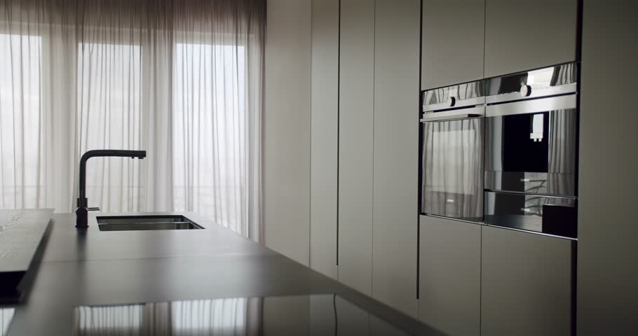 Sleek modern kitchen showcasing minimalist design with built-in appliances, a stylish faucet, and subtle lighting filtered through soft curtains. Modern Kitchen Interior