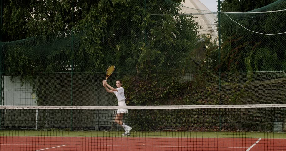A woman play tennis professionally and dynamically in slow motion. Weekend and Sunday activity for recreation. Sports active game with friends. Tennis player in action. Tennis match.