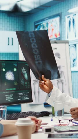 Vertical Video Medic expert showing the x ray imaging test results to patient at check up, discussing about treatment. Doctor pointing at radiography scans for interpretation, diagnostic report