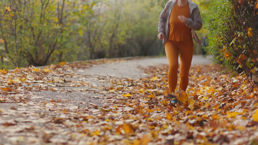 Hello autumn. Full length portrait of fit woman in fitness clothes in the park with headphones running.