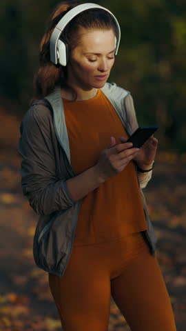 Hello autumn. stylish woman in fitness clothes in the park with headphones.
