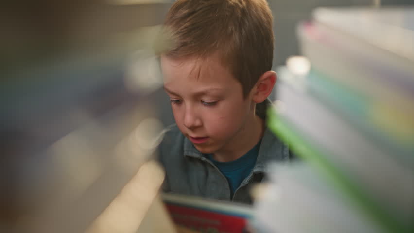 Young Boy Reading a Book at Home Preparing for School Study Learning and Education Concept for a Child Sitting at a Desk Doing Homework. High quality 4k footage