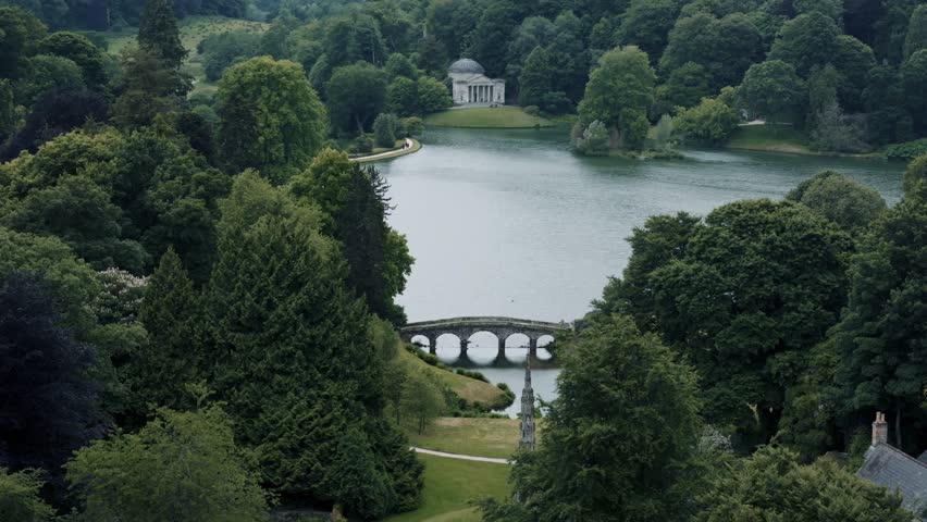 Aerial approach toward the Pantheon at Stourhead Gardens with lake and bridge