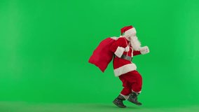 Man in red Santa suit on green background. Santa Claus with sack of presents sneaks on tiptoes and shows gesture secret. - Powered by Shutterstock - Get 15% off with code: PIKWIZARD15