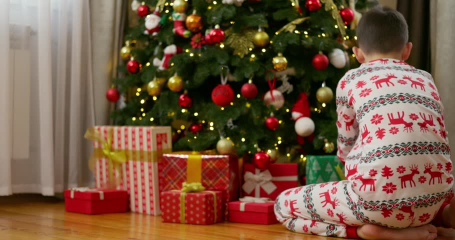 Children opening Christmas presents by festive tree