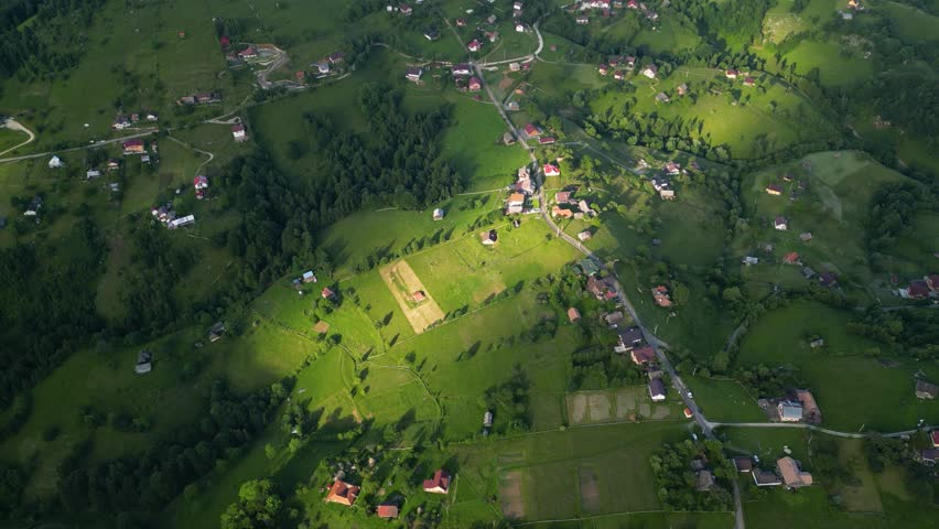 High angle flyover footage over the magnificent picturesque village of Magura in Brasov region of the Romanian Carpati mountains. Drone shot of the gem of romanian tourism on a green summer day.
