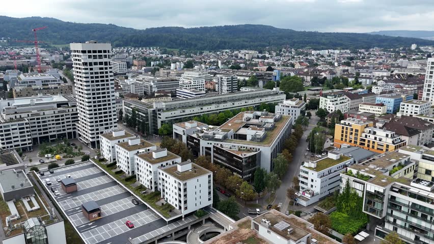 Drone flight over modern city of Zurich with solar panels on roof of apartment blocks. Housing area and homes in luxury swiss town. Forward aerial wide shot.