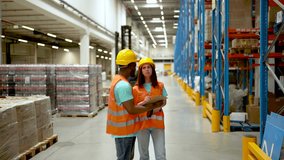 Diverse warehouse workers wearing safety vests and hard hats are discussing inventory using a clipboard and a scanner. The video is in slow motion. - Powered by Shutterstock - Get 15% off with code: PIKWIZARD15