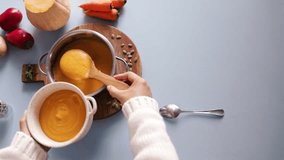 View from above: A hand scoops pumpkin soup with a spoon and lifts it into a bowl. - Powered by Shutterstock - Get 15% off with code: PIKWIZARD15