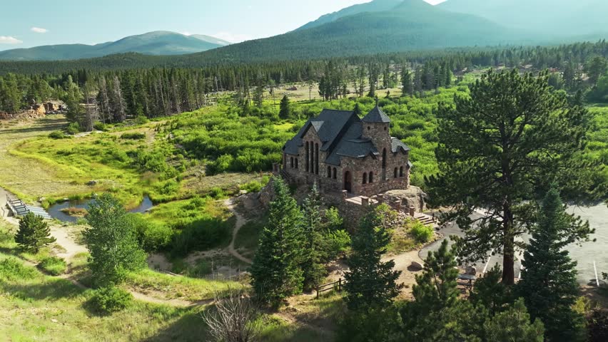 Drone orbit left above stone chapel with immaculate architecture on sunny day in Colorado mountain forest
