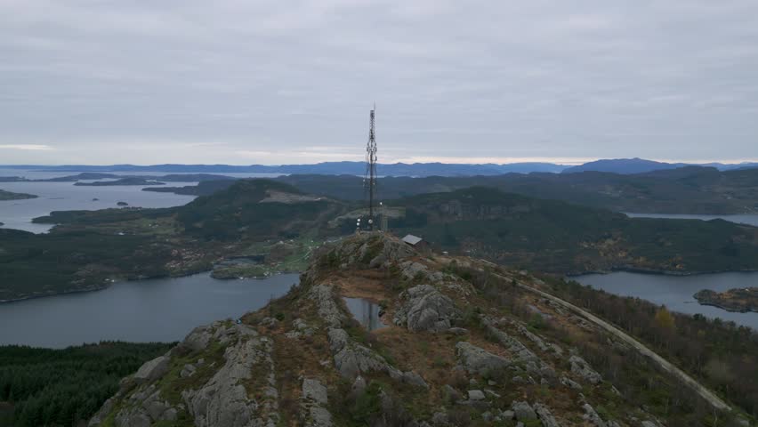 Telecom tower on Lauvåsen mountain overlooking scenic Norwegian fjords and hills, cloudy sky
