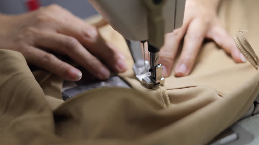 Sewing machines are working, producing clothes in a factory.