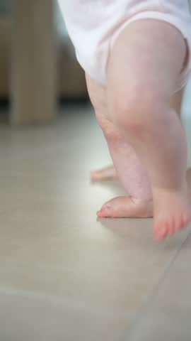 A Cute Baby Moment Taking Its First Steps Indoors While Exploring Their Surroundings,