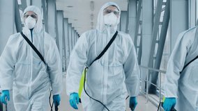 Three healthcare workers in full protective gear walk purposefully down a modern corridor, equipped with tools, signifying readiness for medical procedures or emergency response. - Powered by Shutterstock - Get 15% off with code: PIKWIZARD15