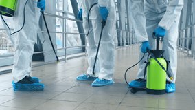 A team dressed in protective suits prepares to disinfect a public area, ensuring safety from pathogens. They focus on cleanliness in a busy indoor environment while wearing safety gear. - Powered by Shutterstock - Get 15% off with code: PIKWIZARD15